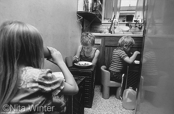 Children eating on crates in homeless hotel room, Tenderloin San Francisco
