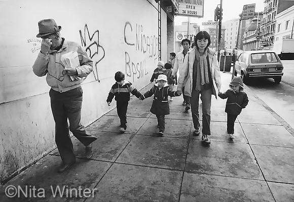 Teacher with 3 preschoolers on sidewalk under adult theater sign Children of the Tenderloin_x1550