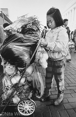 Young girl with loaded cart at Civic Center Farmers Market, San Francisco