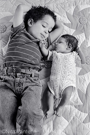 Brother and newborn sister on sunflower quilt _grayscale