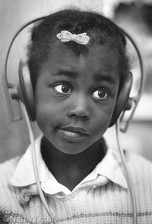 Girl listening to story about tiger on earphones_Childcare center Tenderloin San Francisco